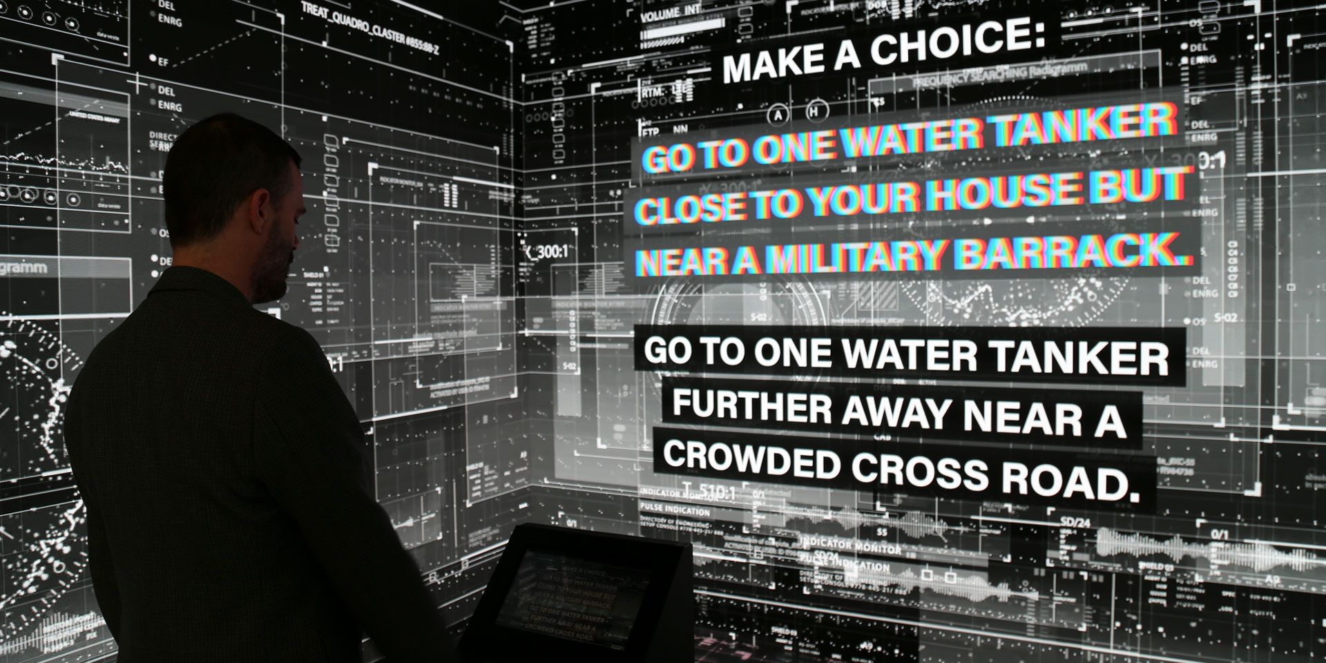 A man stands in front of a screen simulating a digital environment. 