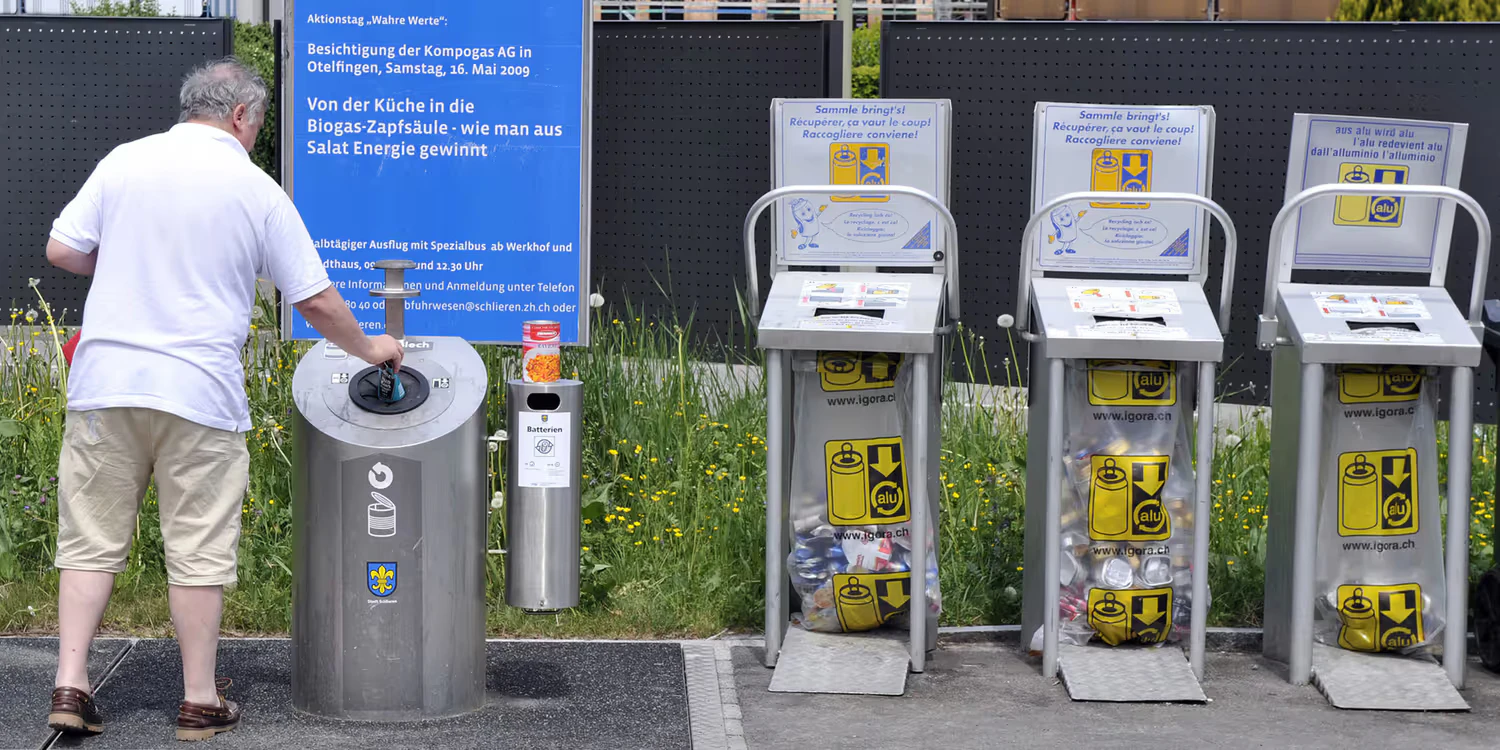 A man recycles a tin can. Three collection points for aluminium drink cans are also pictured. 