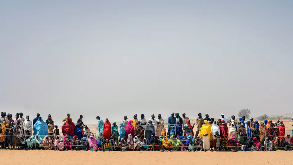 A group of people stand in a line behind a fence.