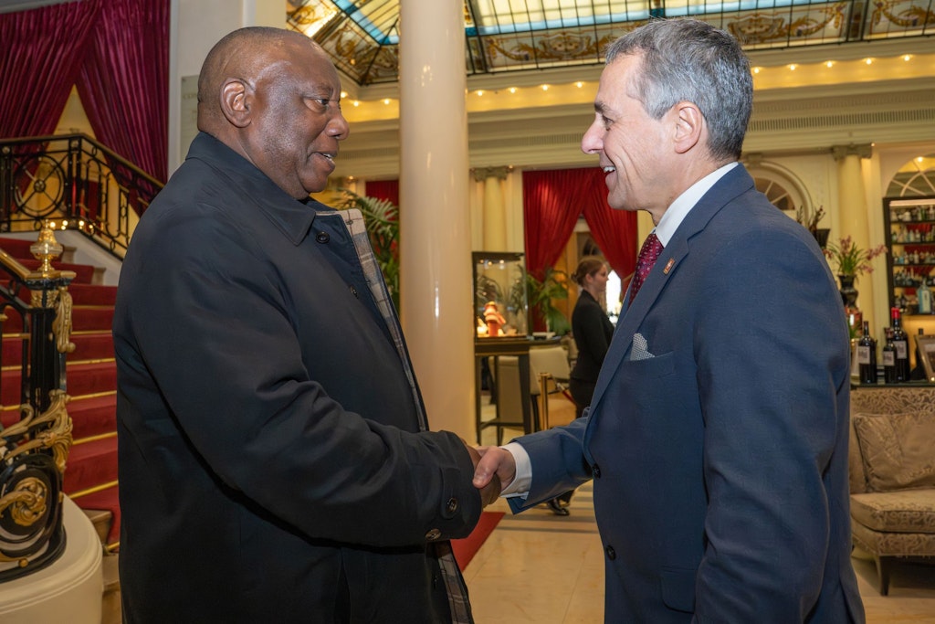 Two men greet each other in a festive room.