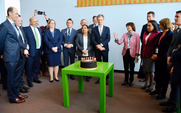 Representatives of the ACT group standing around a cake.