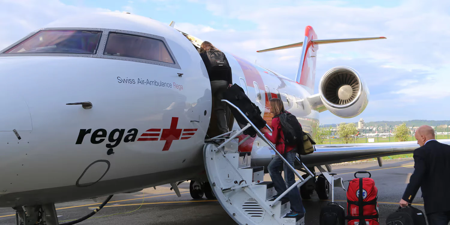 The rapid response team of the Swiss Humanitarian Aid Unit boards a white REGA aircraft on the tarmac at Zurich Airport.