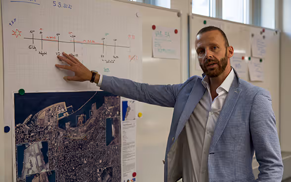 Operations manager Silvio Flückiger points to a city map of Beirut hanging on the wall in the Swiss Humanitarian Aid crisis room.