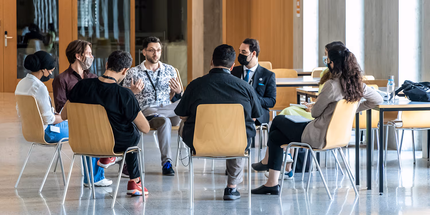 Young participants of the MEM Summer Summit sitting on chairs in a circle and discussing a topic.