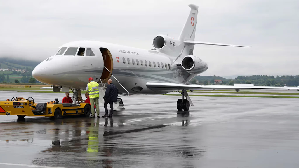 Two men standing in front of an aircraft on the tarmac at Bern-Belp airport. 