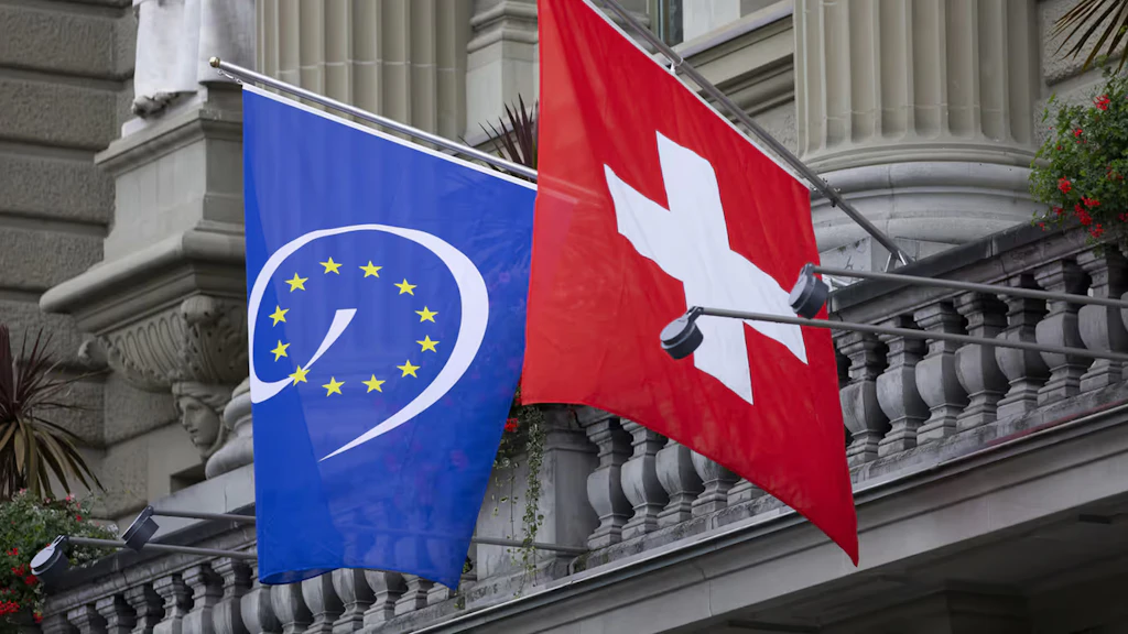 The national flag of Switzerland and the flag of the Council of Europe hanging on the Federal building.
