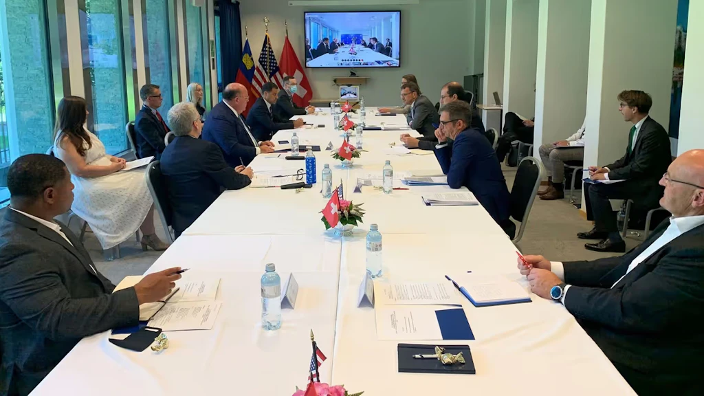 Several people at a conference table in Switzerland talk via video conference with colleagues in America.