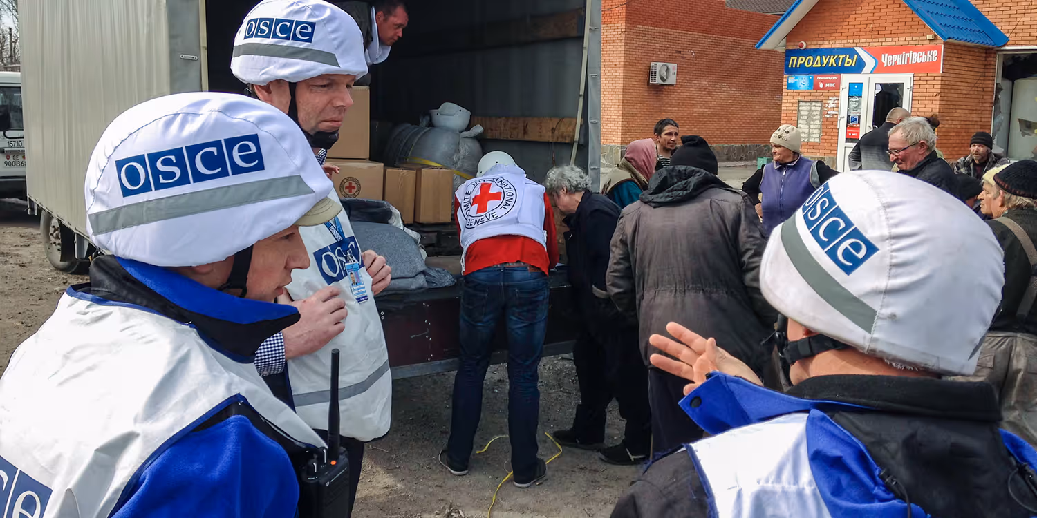 Three members of the OSCE mission observe the delivery of aid packages to the Ukrainian population.