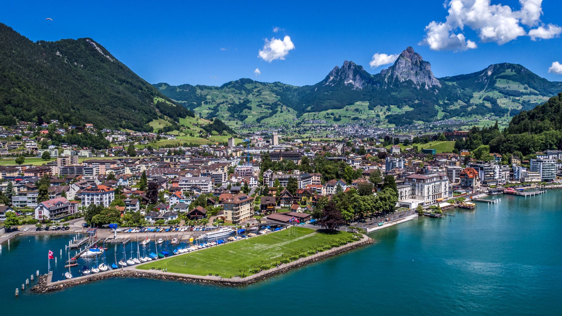 View of the town of Brunnen from above, with the Square of the Swiss Abroad clearly visible and the lake and mountains in the background.