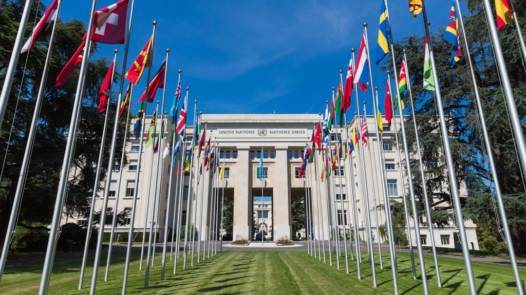 Waving flags stand in two rows in front of the Palais des Nations.