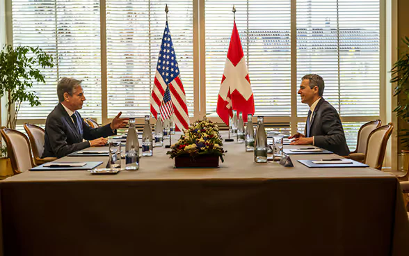 President Cassis and Foreign Minister Blinken sit across from each other at a table and talk.