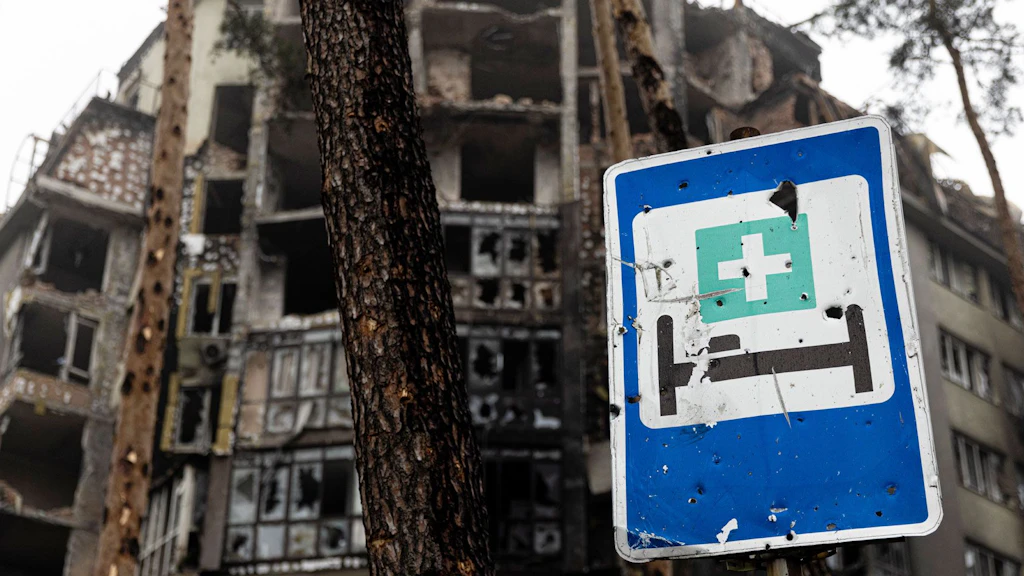 Destroyed buildings and a sign indicating a hospital.