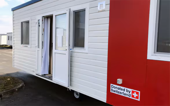 A mobile housing unit with the inscription "donated by Switzerland"