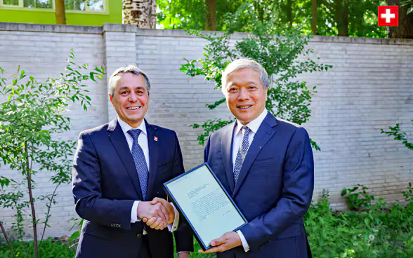 Federal Councillor Ignazio Cassis and Ambassador Zhu Liying shake hands. 