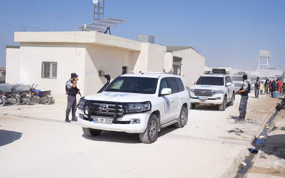 White UN vehicles pass a checkpoint.