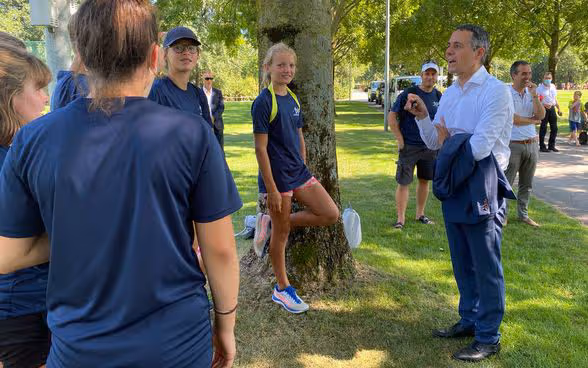 Federal Councillor Ignazio Cassis talks to track and field athletes outdoors. 