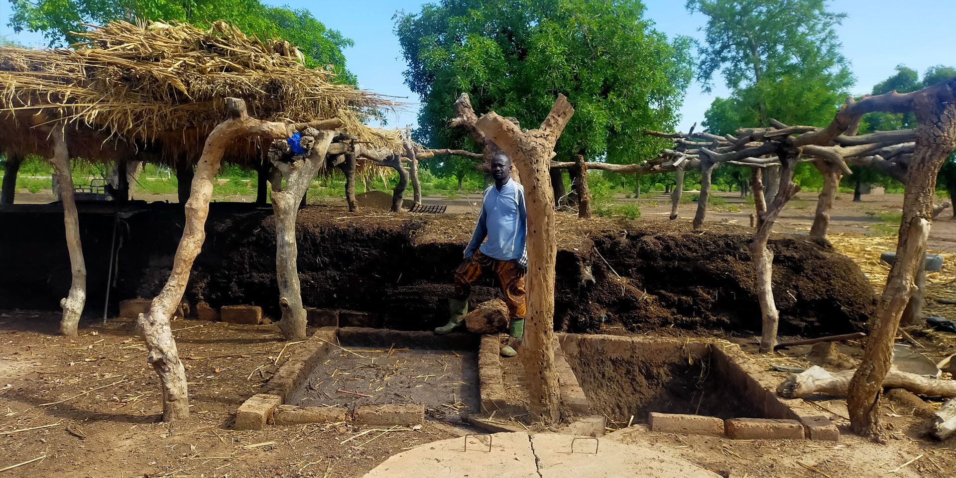 A farmer from Burkina Faso stands next to a compost heap.
