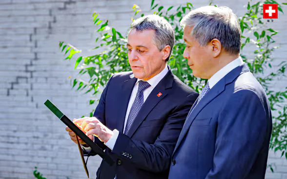 Federal Councillor Ignazio Cassis and Ambassador Zhu Liying examine a document. 