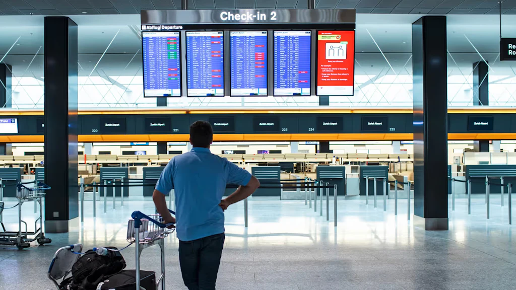  A man studies the departure schedule in the departure hall of an airport. 