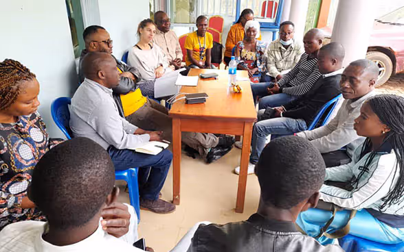 A group of people in Congo talks sitting around a table.