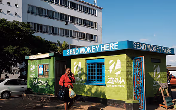 Woman walking past a cash transfer agency. 