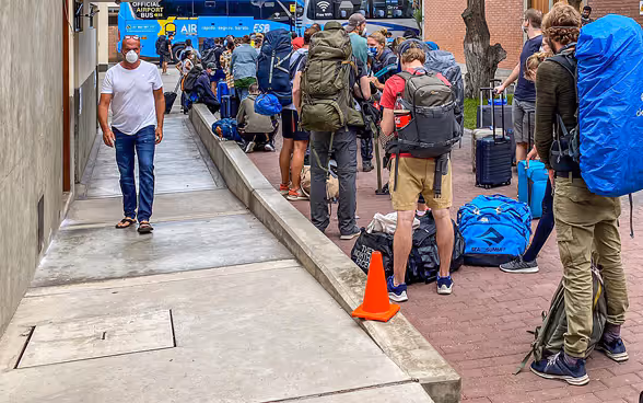 Travelers line up to get on the bus. In the background are two more buses of the Swiss convoys. 