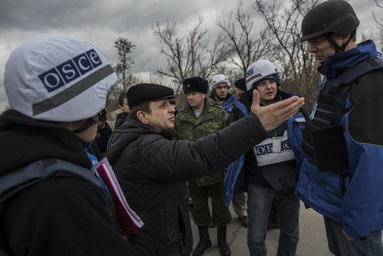 OSCE personnel in Ukraine talking to a man outdoors.