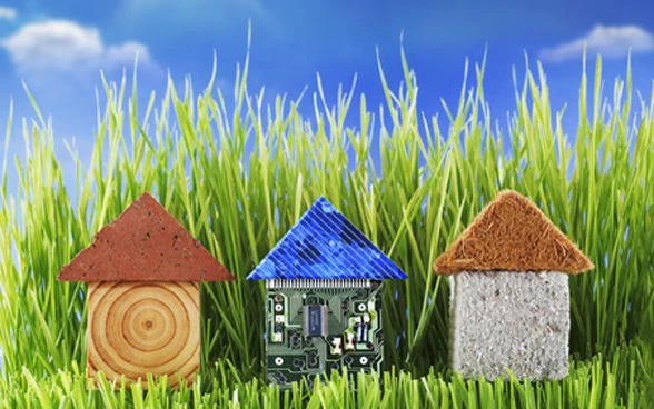 Three small toy houses in a row, on grass.