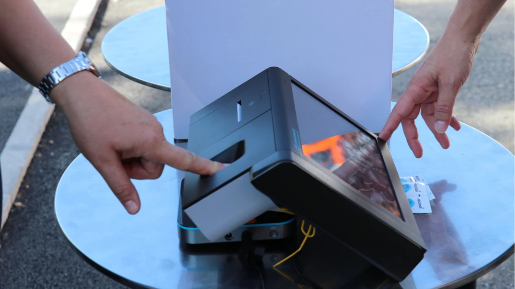 The image shows a citizen trying out a new voter registration device.
