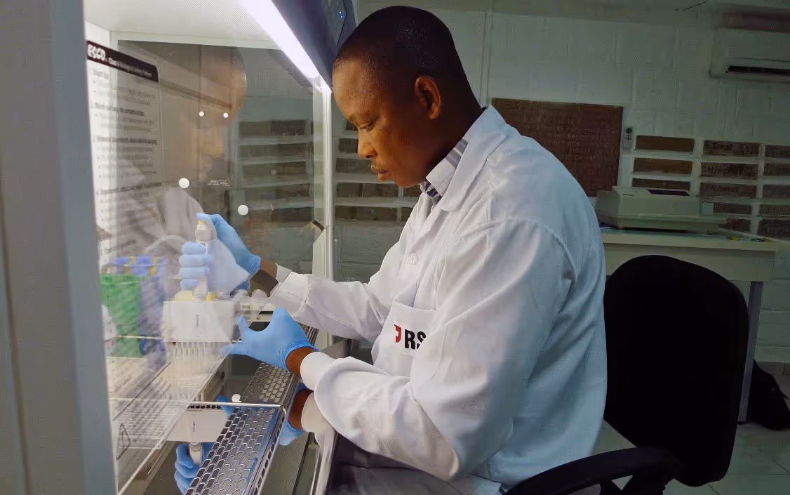 A researcher in a laboratory carries out analysis under a microscope