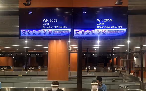 Deux écrans dans la salle d'embarquement de l'aéroport de Yangon montrent le vol vers Zurich.