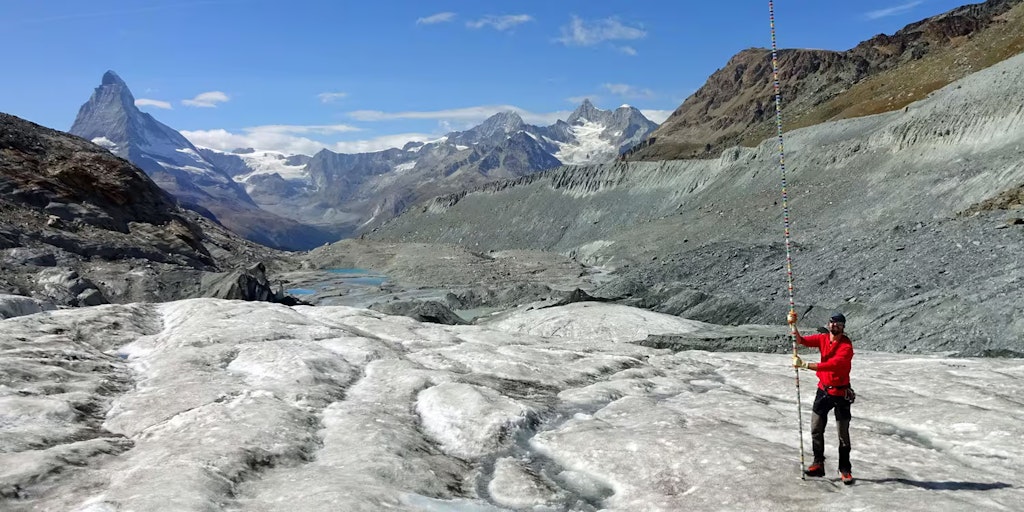 Un homme équipé d’une perche de mesure sur un glacier dans les Alpes suisses.