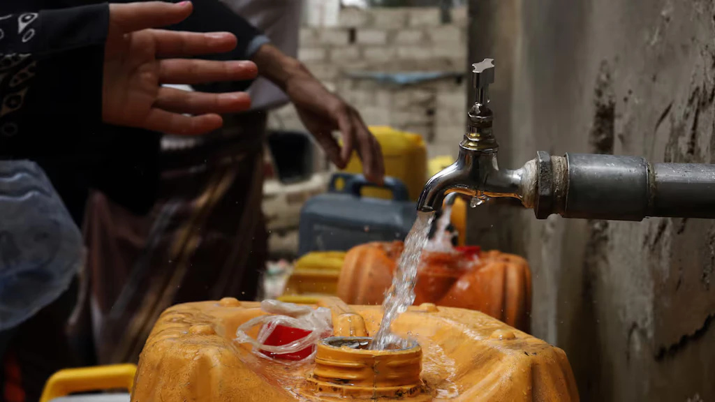 De l’eau potable coule d’un robinet dans un bidon jaune. 