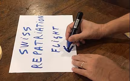 Une feuille de papier est posée sur une table sur laquelle est écrit à la main «vol de rapatriement suisse».