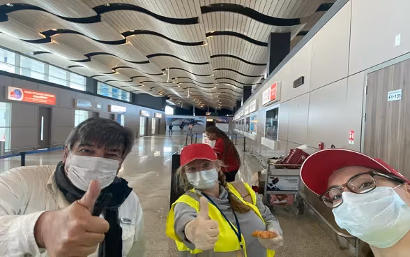 Pouces levés, casquettes aux couleurs helvétiques et masques sont de rigueur pour une pose photo à l’aéroport de Dakar avant le prochain départ d’un vol pour la Suisse.