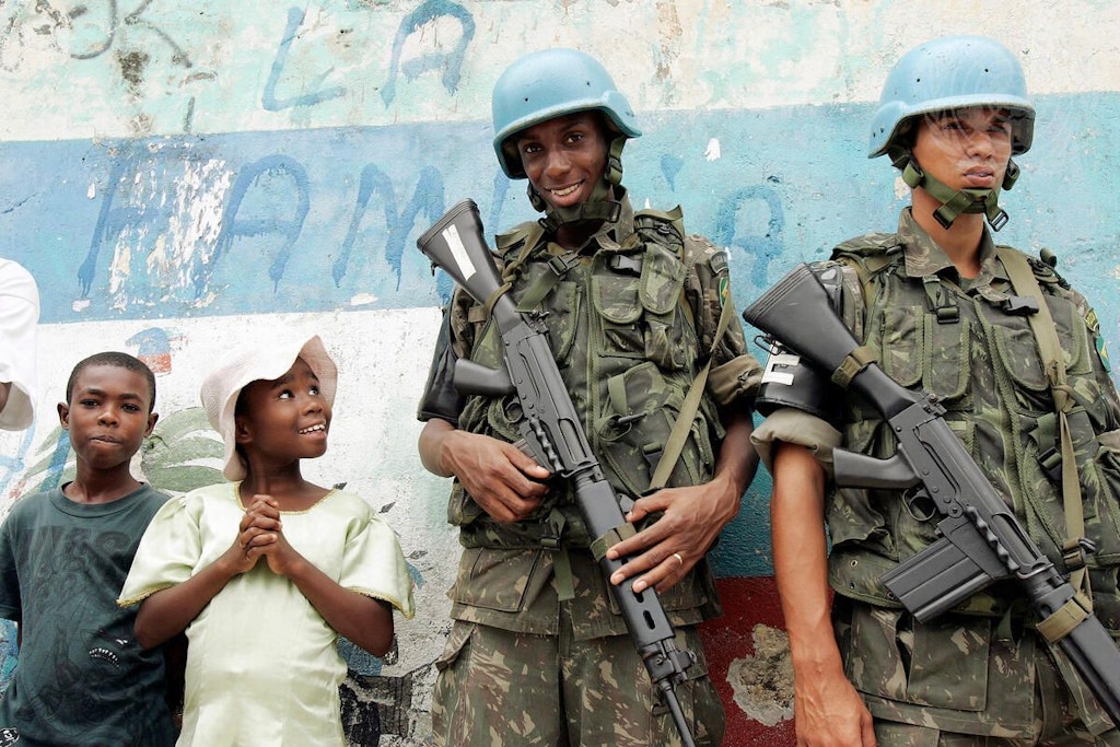 Deux soldats d’une force de maintien de la paix de l’ONU debout à côté de deux garçons.
