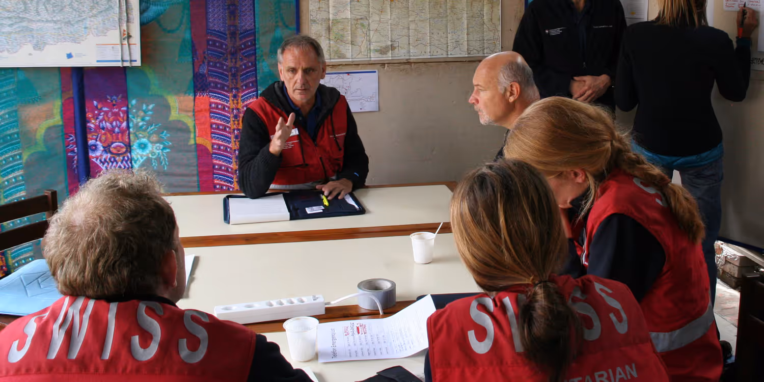 Dans une baraque de fortune, Ueli Salzmann instruit son équipe sur une intervention à venir.