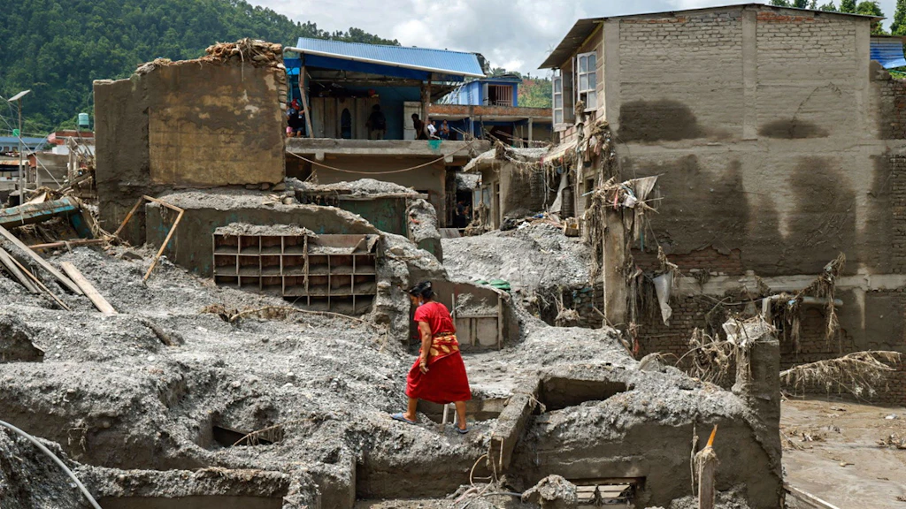 Une femme enjambe les décombres d'une maison détruite.