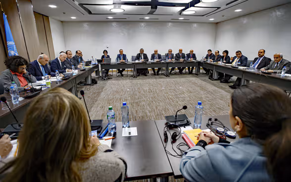 Des femmes et des hommes assis autour de la table des négociations.