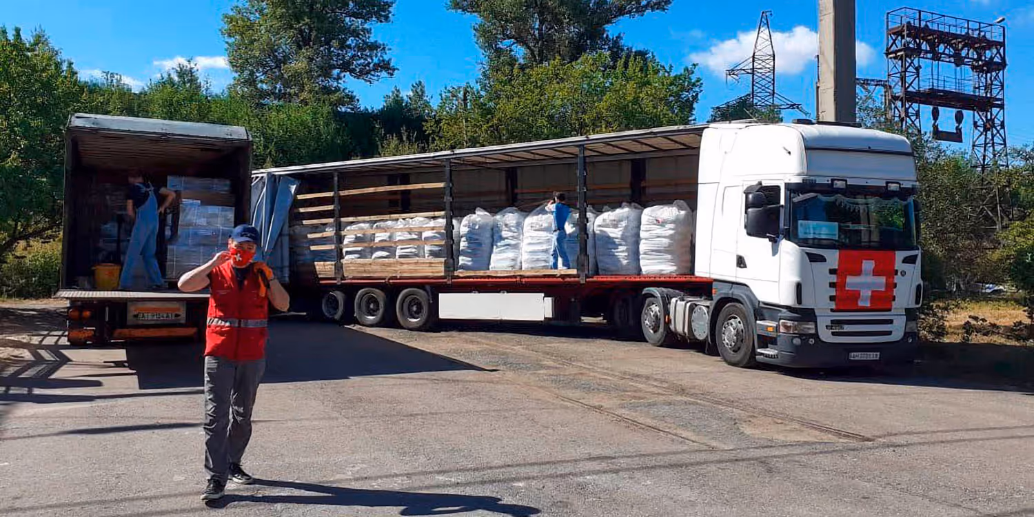 des logisticiens de l'aide humanitaire suisse chargent des fournitures de secours dans un camion.
