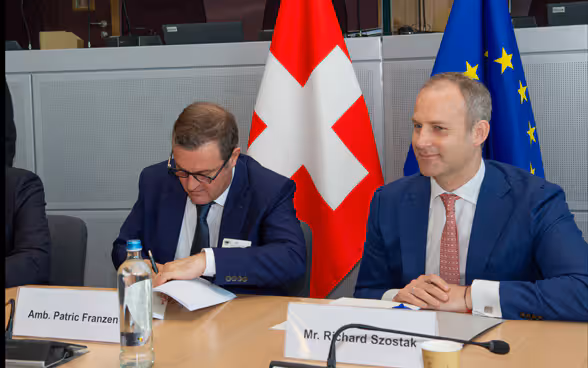 Les négociateurs en chef suisse Patric Franzen et européen Richard Szostak paraphent l’accord sur les programmes à Bruxelles.