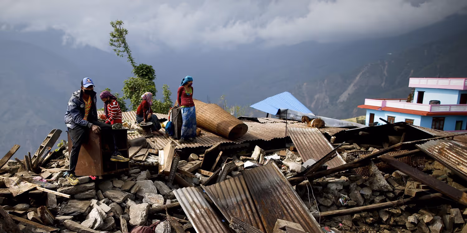 Une famille népalaise avec deux enfants est assise sur les décombres de sa maison dans un village de montagne.
