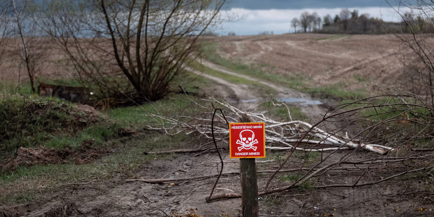 Un panneau rouge avec une tête de mort placé sur un chemin signale la présence d’un champ de mines.