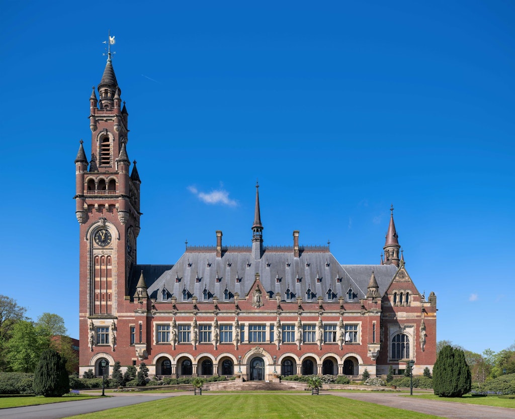 Le Palais de la Paix à La Haye sous un ciel bleu, bâtiment historique avec tour abritant d’importantes juridictions internationales.