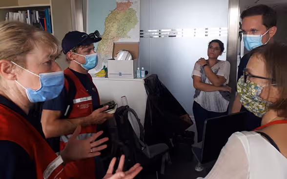 Des experts du Corps suisse d'aide humanitaire discutent, dans un bureau, des mesures à prendre.