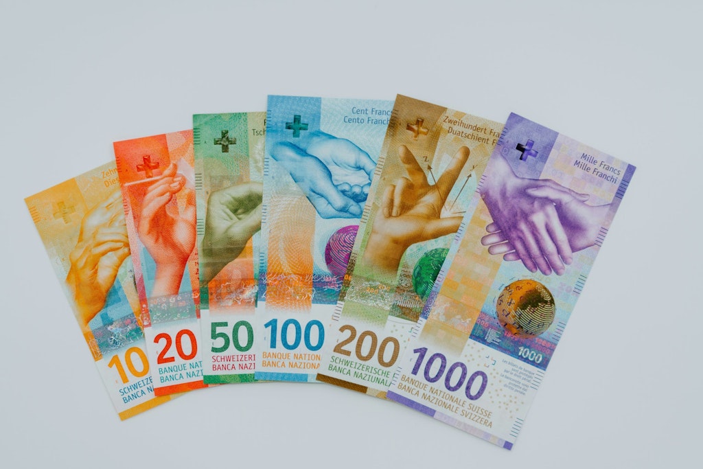Billets de banque suisses d'une valeur comprise entre 10 et 1000 francs disposés sur un fond blanc.