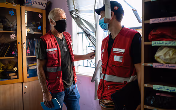 Deux experts du Corps suisse d'aide humanitaire s'entretiennent dans une salle de classe détruite.