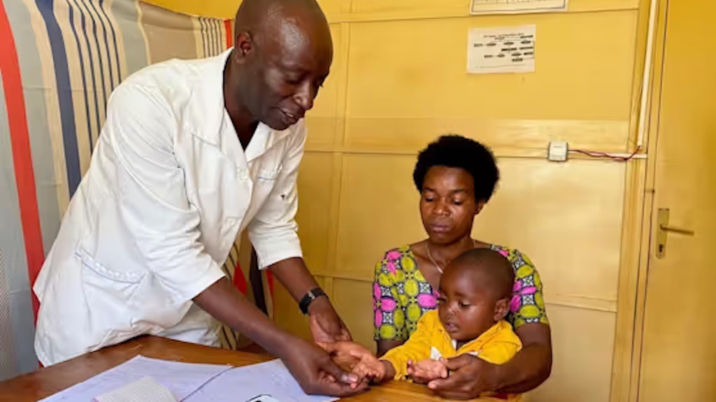 Un médecin examine un enfant dans les bras de sa mère.