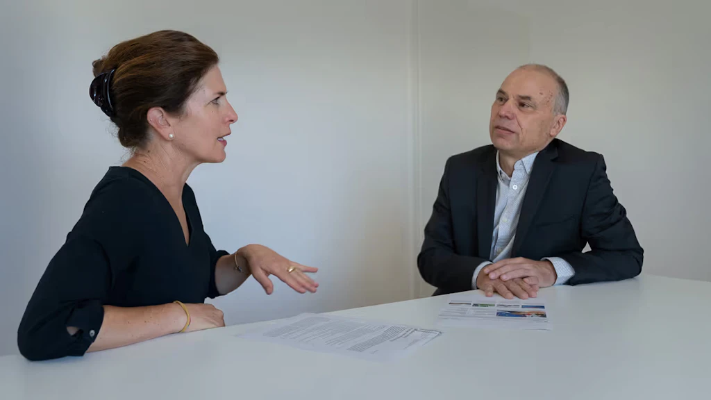 Debora Kern et Daniel Birchmeier, assis à la même table, consultent des documents et sont engagés dans une discussion animée. 