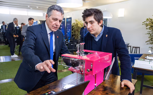Un jeune homme montre à Ignazio Cassis le fonctionnement d'une machine.